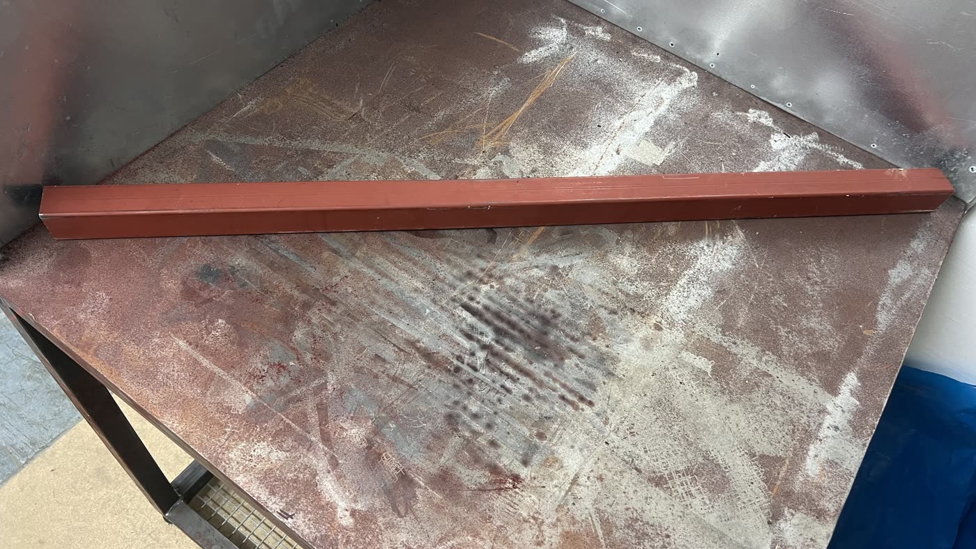 Red painted steel section before laser cleaning