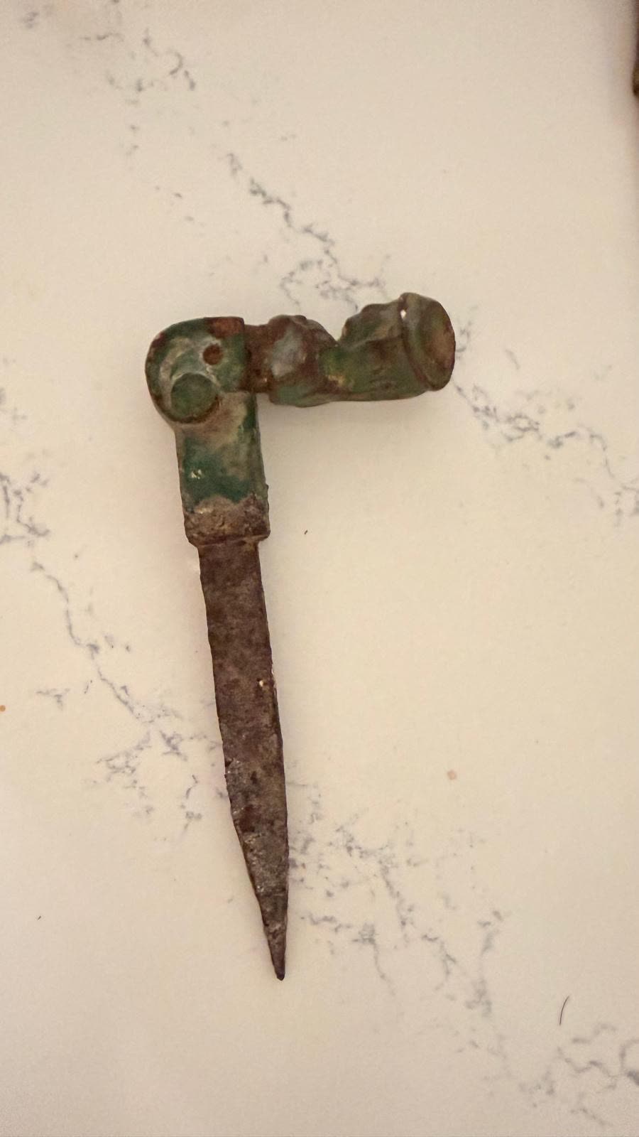 A second cast iron shutter hinge before cleaning, with green paint over corrosion